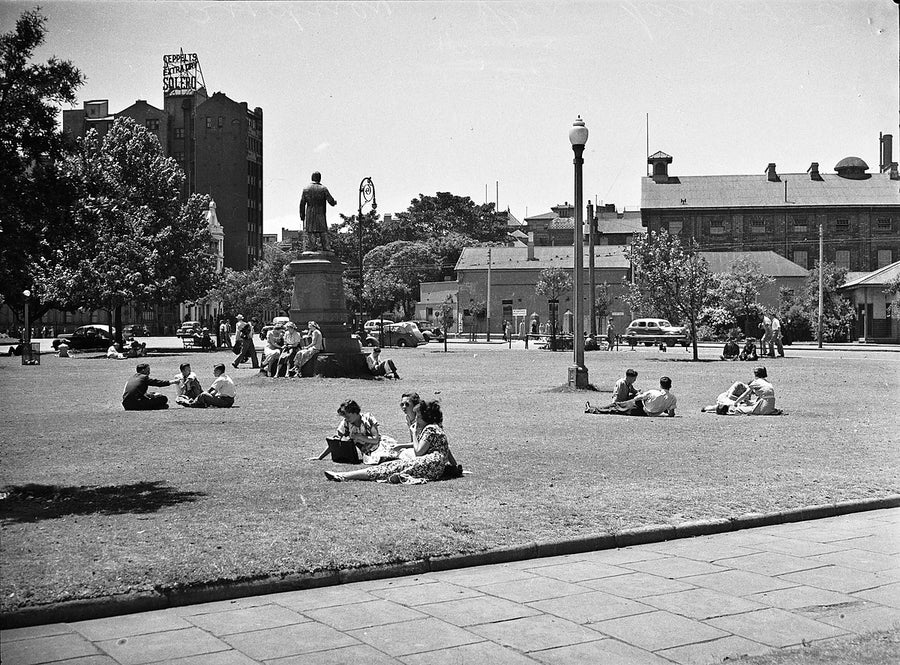 People relaxing on a Sydney park lawn beside a bronze statue — photograph, from Sydney, 1950