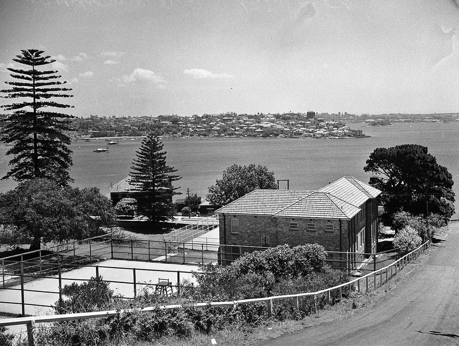 Harbour view past a tennis court and brick house — photograph, 1950