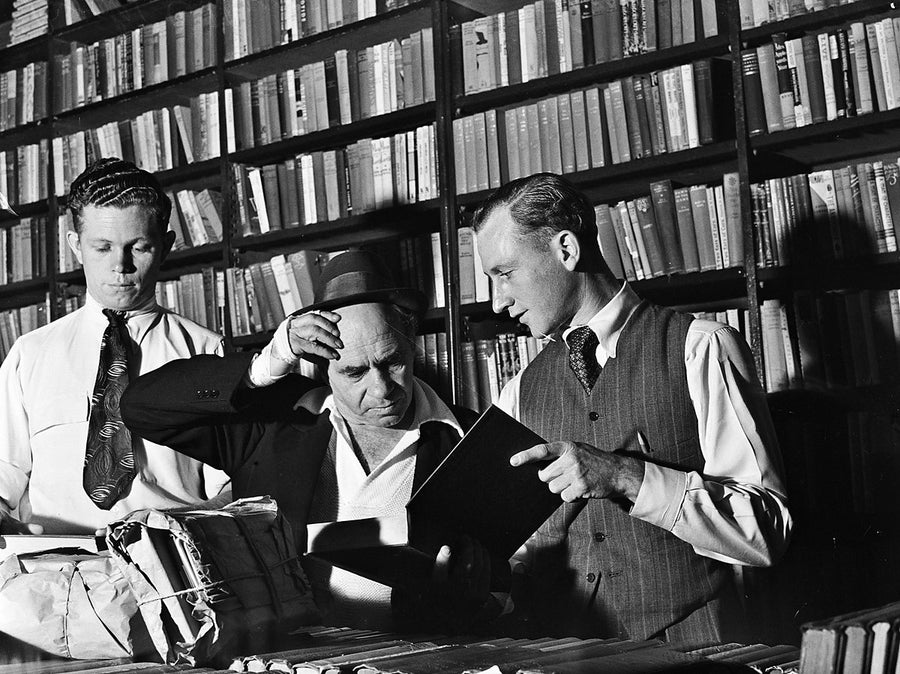 Examining books at a Marrickville book collection — photograph, from Marrickville, 1949
