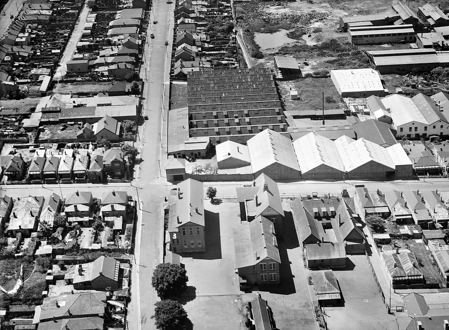 Aerial over a Marrickville industrial pocket: saw-tooth factories and terrace streets — photograph, from Marrickville, after 1935