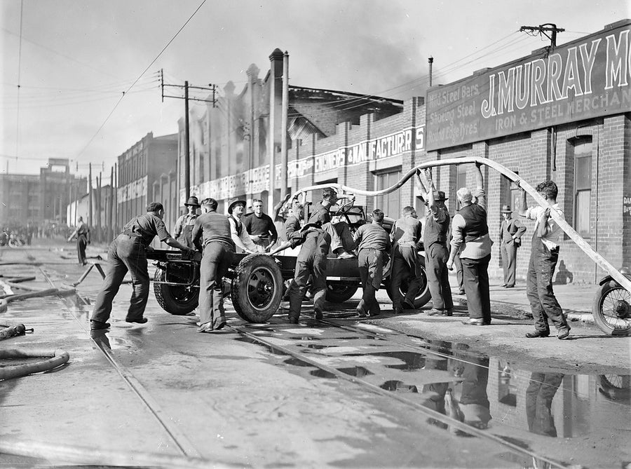 Salvaging a motor chassis at the Phillip Street fire, Redfern — photograph, from Phillip Street, 1934