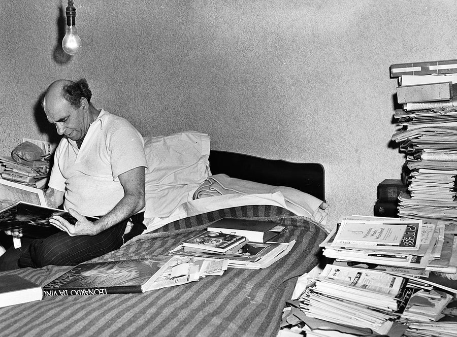 Book collector reading among stacked volumes, Marrickville — photograph, from Marrickville, 1949