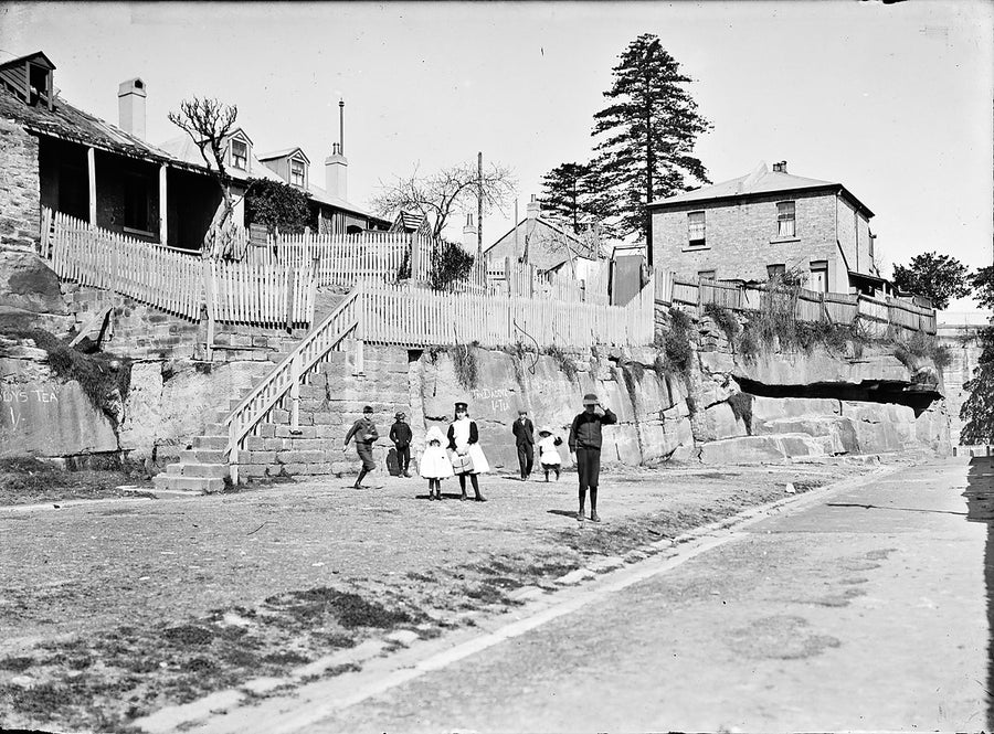 Children beneath the rock-face cottages, The Rocks, Sydney — photograph, from The Rocks, c. 1890–1910
