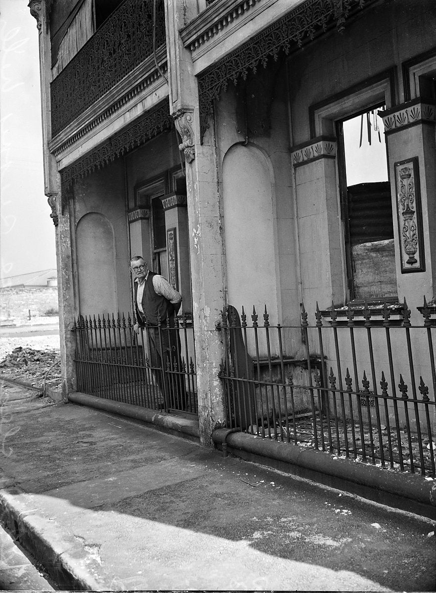 Man at the fence of a cast-iron terrace house, Surry Hills, 1950 — photograph, from Surry Hills, circa 1950