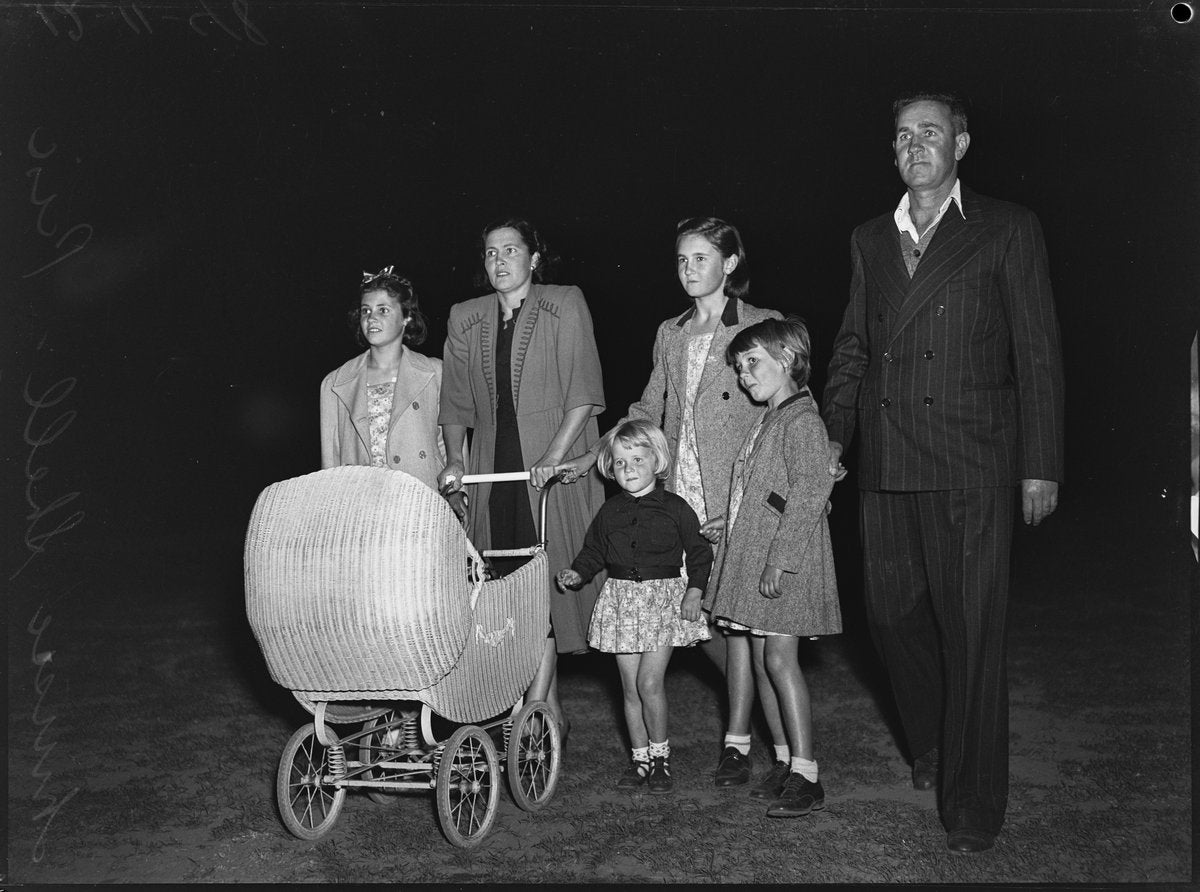 Family with a wicker pram at night, North Sydney, 1948 — photograph, from St Leonards Park, North Sydney, circa 1948