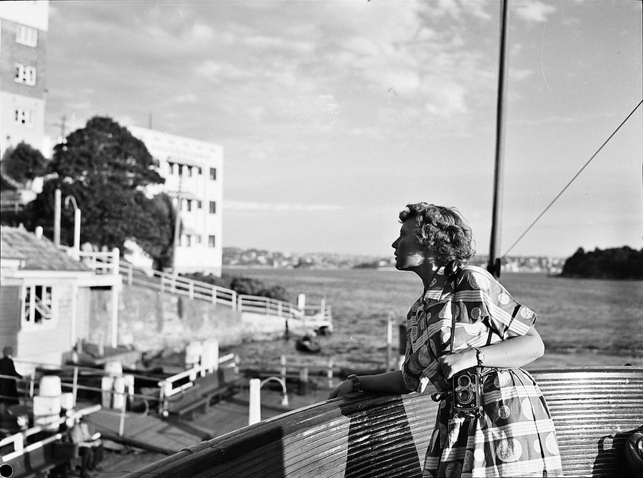 Qantas hostess with a twin-lens camera on the Mosman ferry, ca. 1950 — photograph, from Mosman Bay, circa 1950