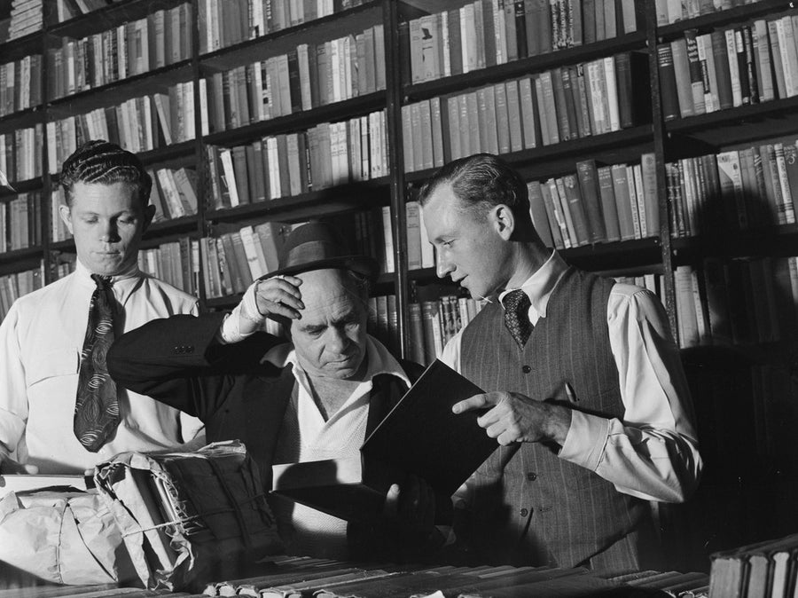 Examining books at a Marrickville book collection — photograph, from Marrickville, circa 1949