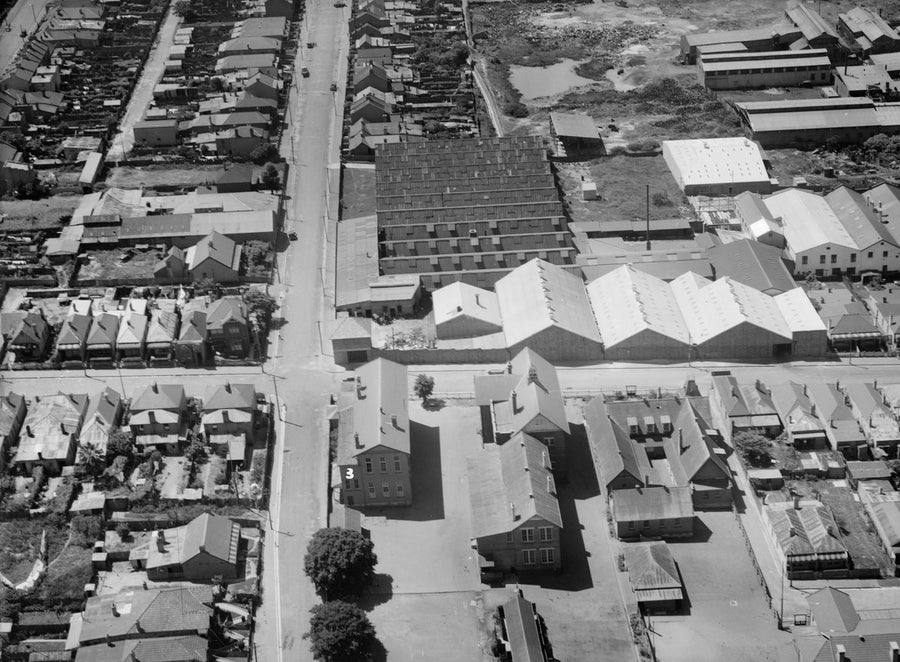 Aerial over a Marrickville industrial pocket: saw-tooth factories and terrace streets — photograph, from Marrickville, circa 1935