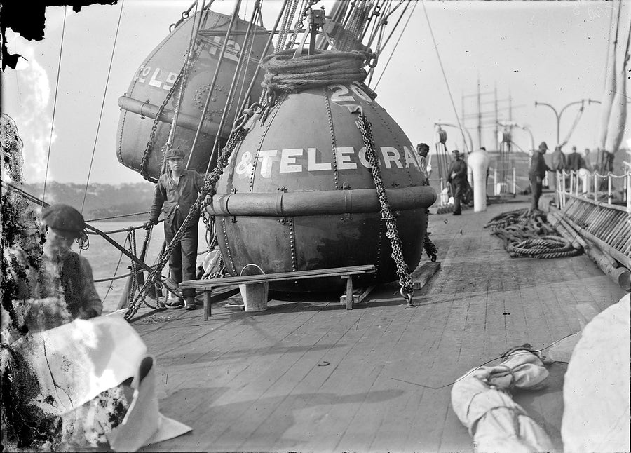 Pacific cable sphere lettered '& TELEGRA' on a ship's deck — photograph, circa 1905