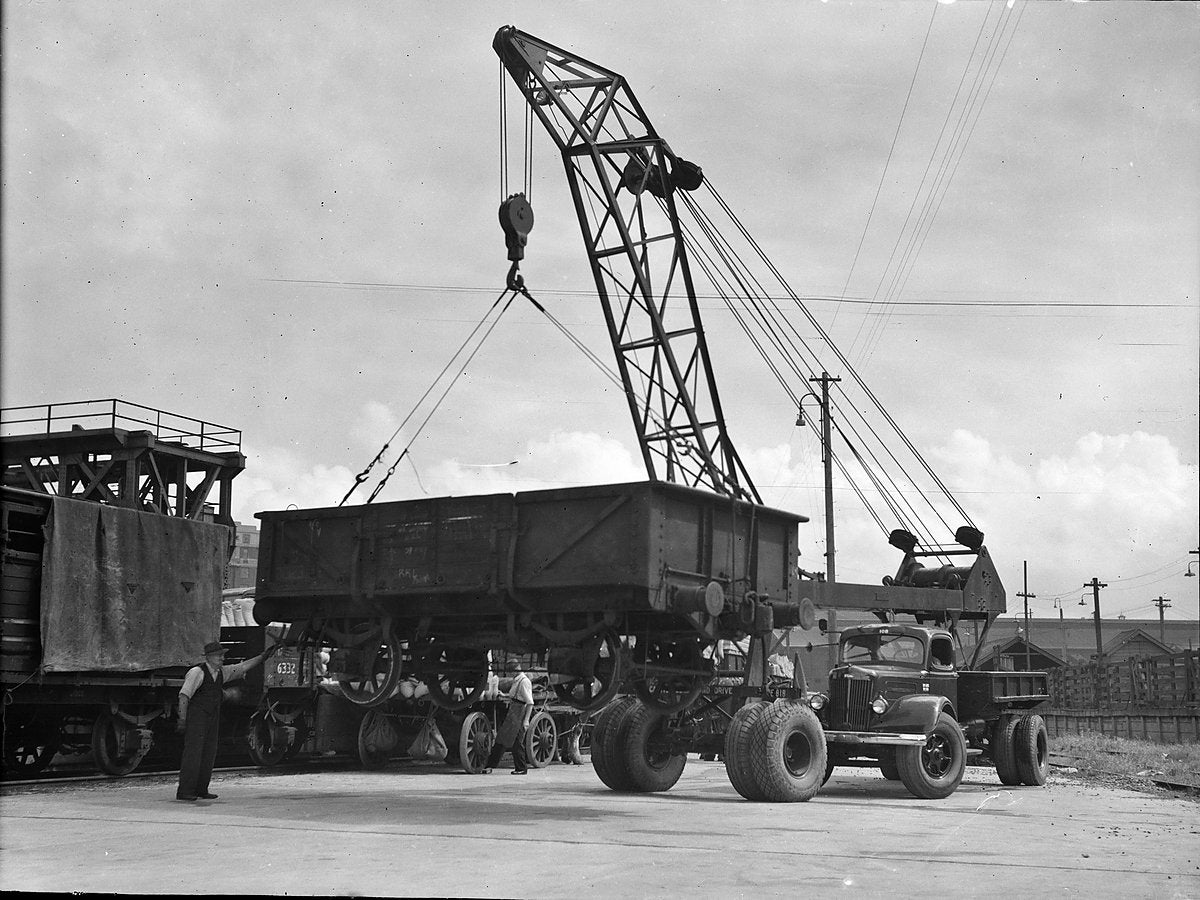 Truck-mounted crane lifting a railway wagon, Sydney — photograph, from Sydney CBD, circa 1935