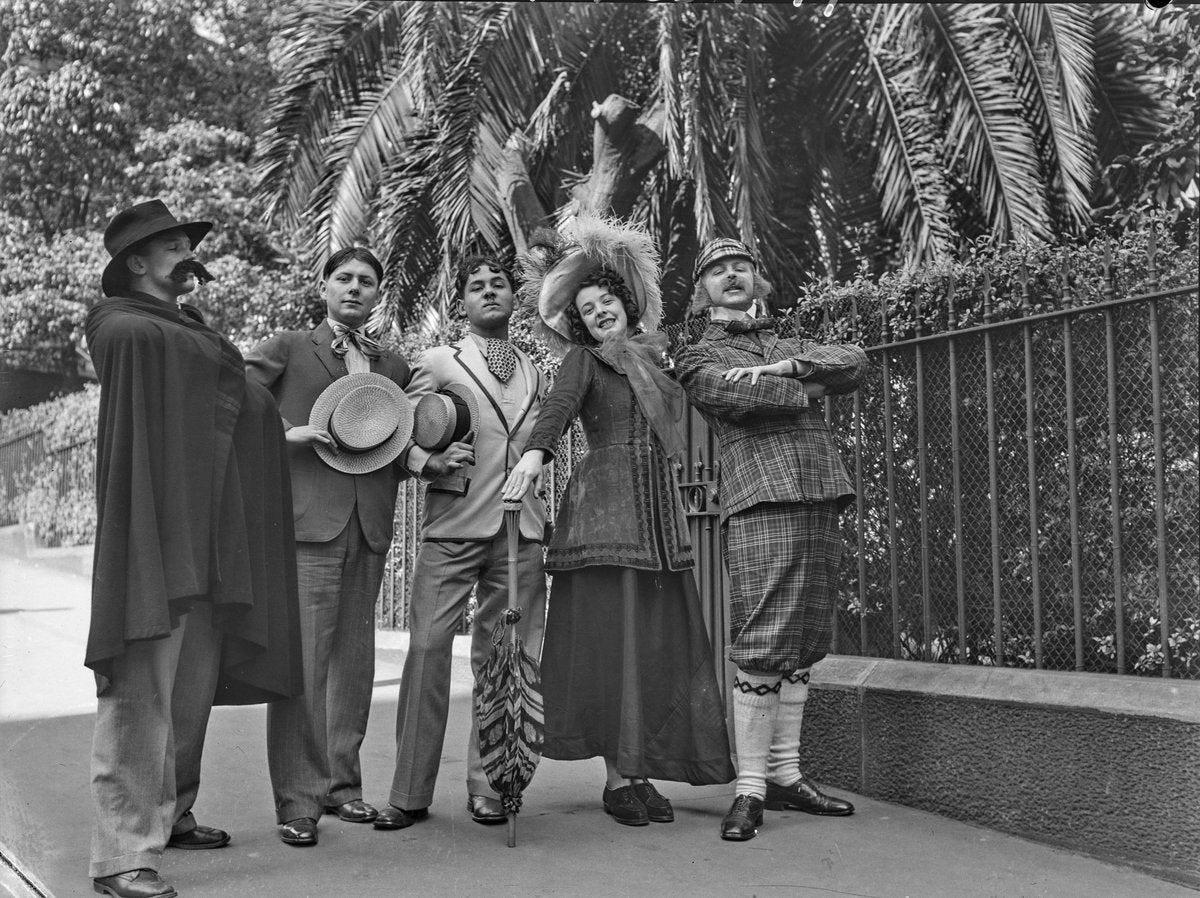 Five performers in theatrical costume beside a wire fence — photograph, circa 1933