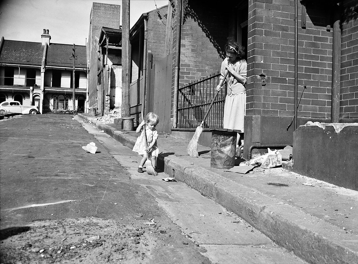 Woman and child sweeping outside a terrace house, Redfern or Surry Hills, 1950 — photograph, from Redfern, circa 1950