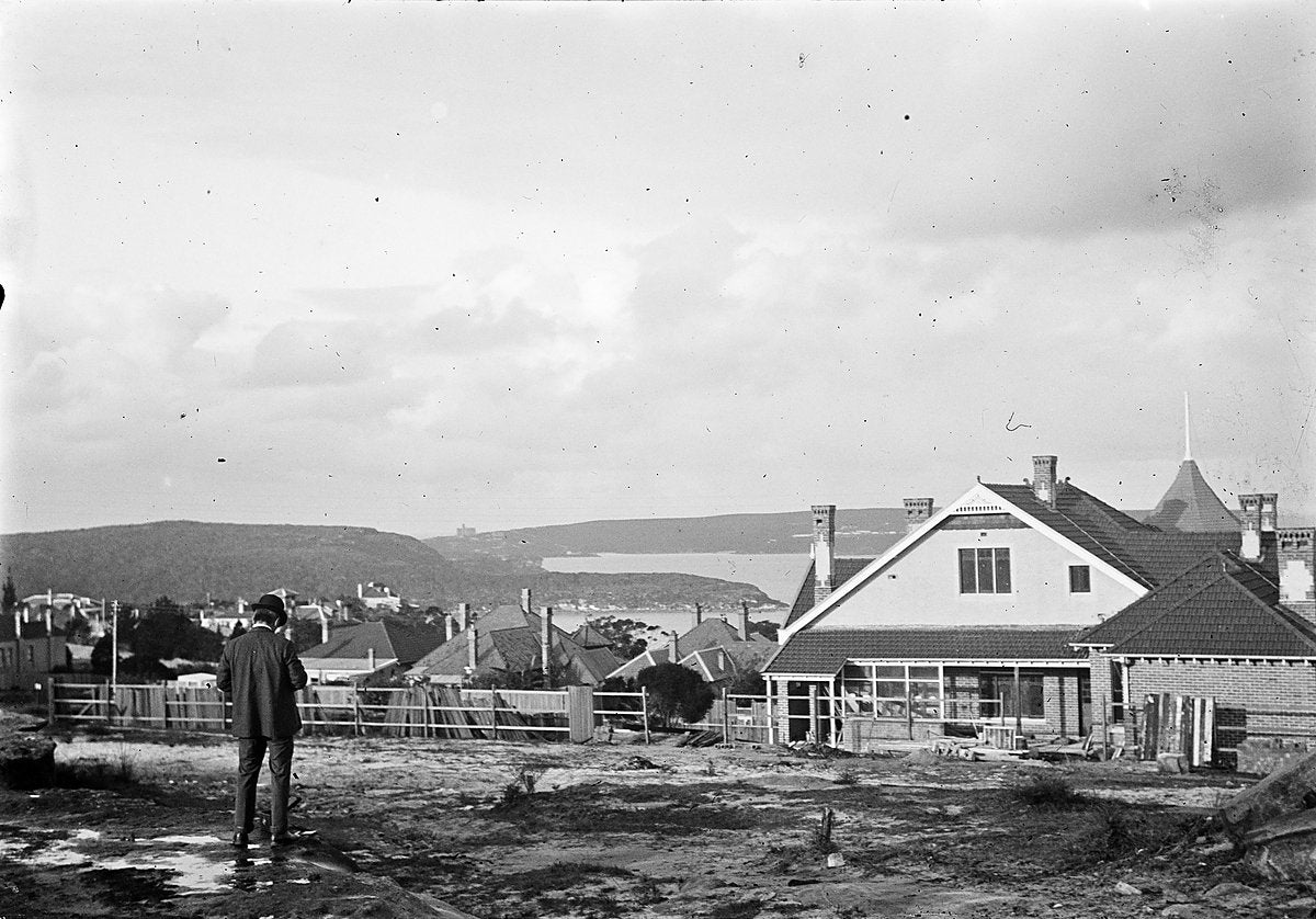 Man standing on a cleared block above a harbour inlet, Sydney — photograph, circa 1900