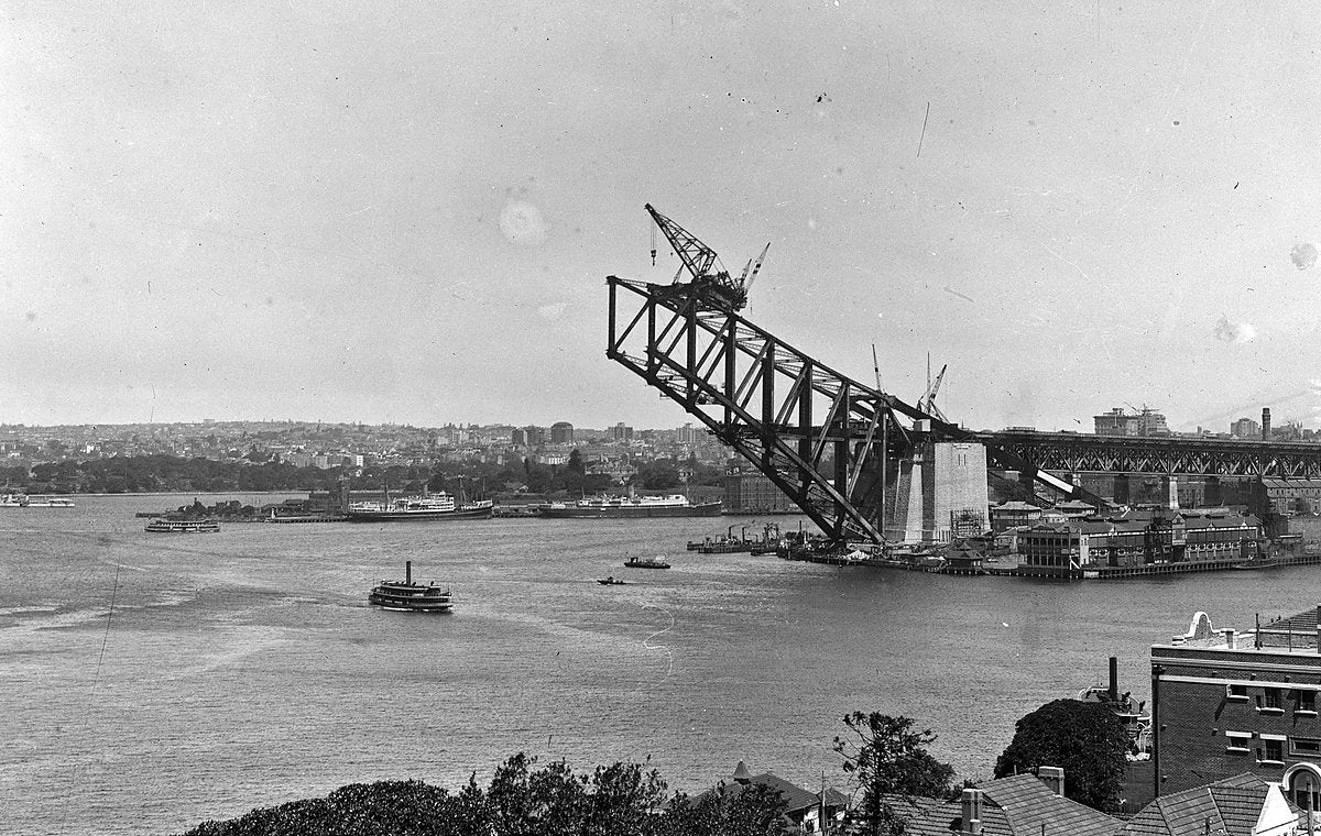 Southern arch of the Sydney Harbour Bridge cantilevered over the harbour — photograph, from Sydney Harbour Bridge, 1930