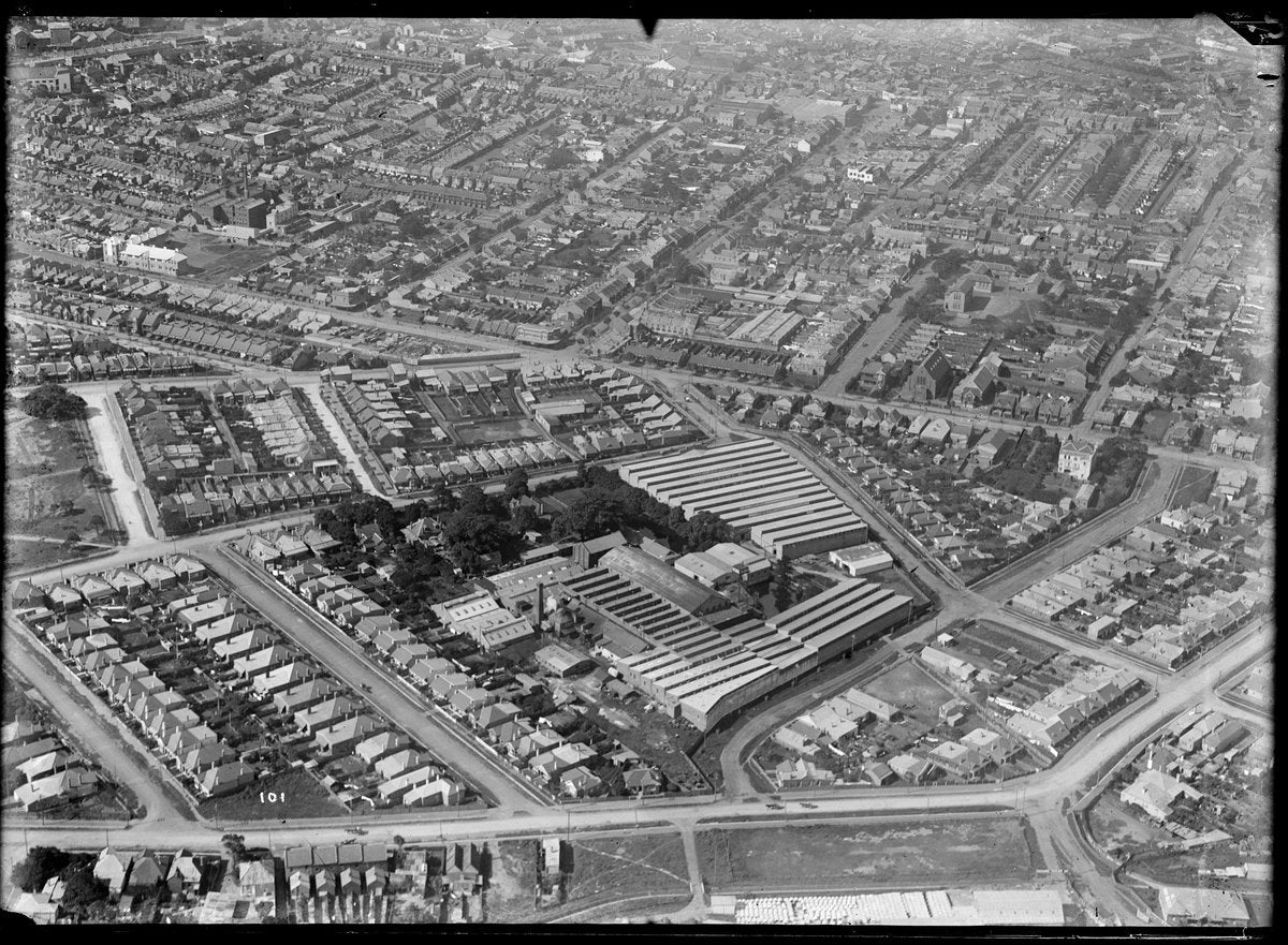 Sawtooth-roofed factory works ringed by terraced streets, inner Sydney — photograph, circa 1937
