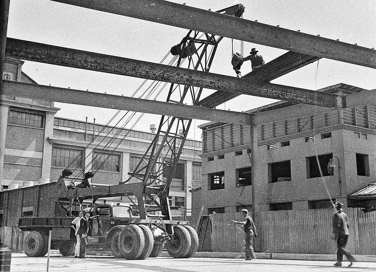 White truck-mounted crane hoisting steel girders, Darling Harbour — photograph, from Darling Harbour, 1949
