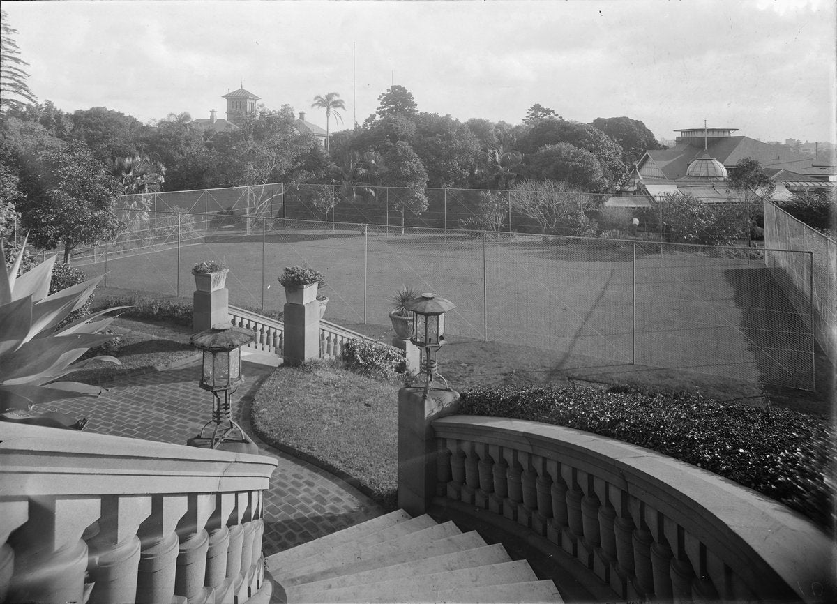 Balustraded garden stair above a netted lawn tennis court — photograph