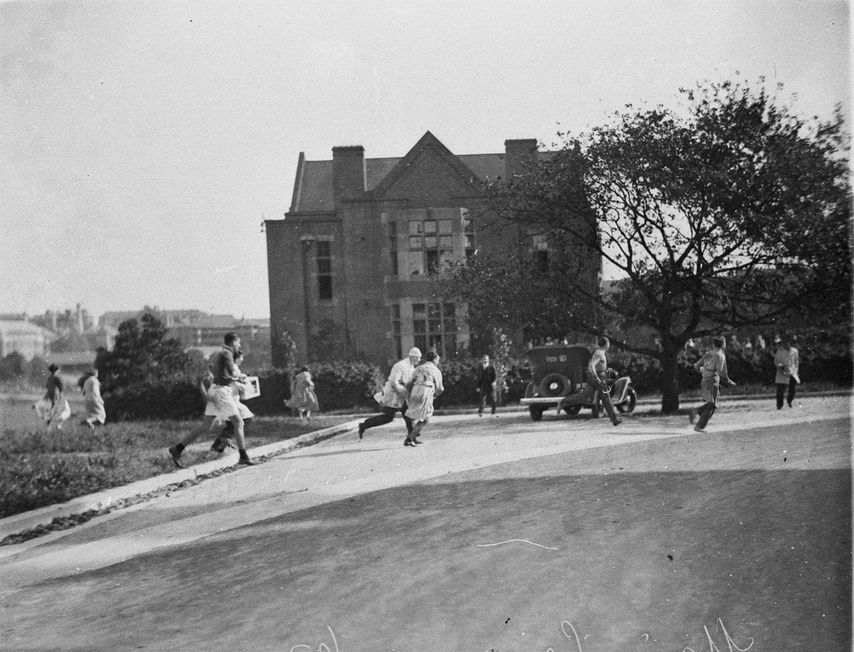 Students running past a brick building, Sydney University Commemoration Day, 1932 — photograph, from University of Sydney, New South Wales, circa 1932