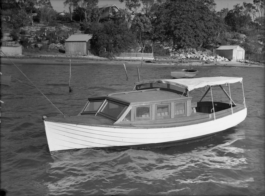 Timber cabin launch with canvas canopy off boat-shed shore — photograph, circa 1938