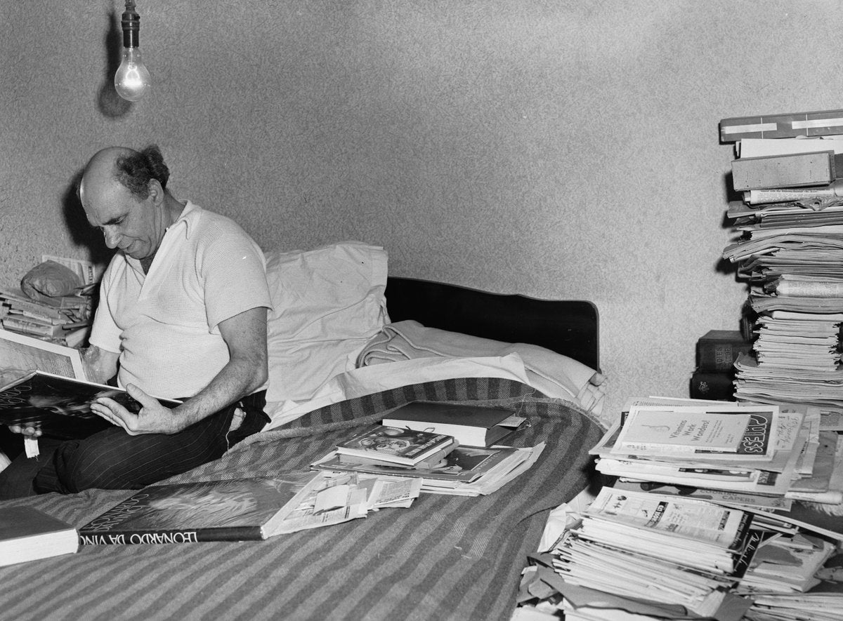 Book collector reading among stacked volumes, Marrickville — photograph, from Marrickville, circa 1949