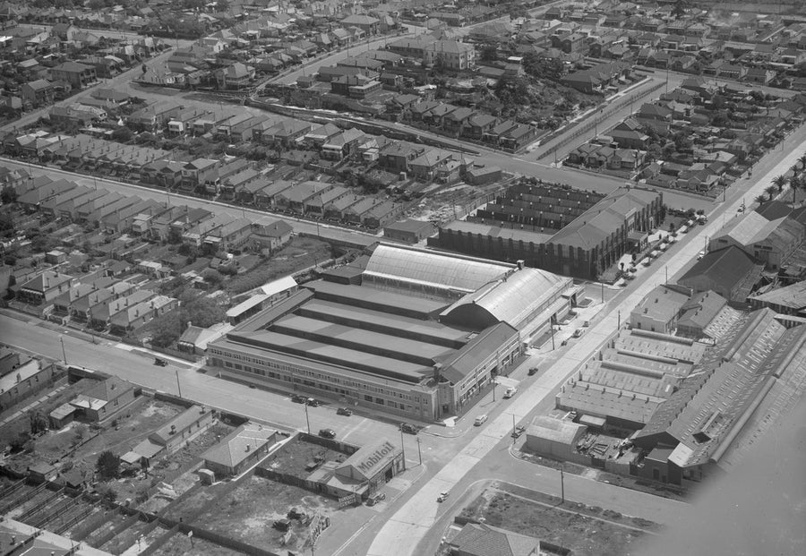 Sawtooth-roofed factory among terraced streets, aerial view — photograph, from Marrickville, circa 1940